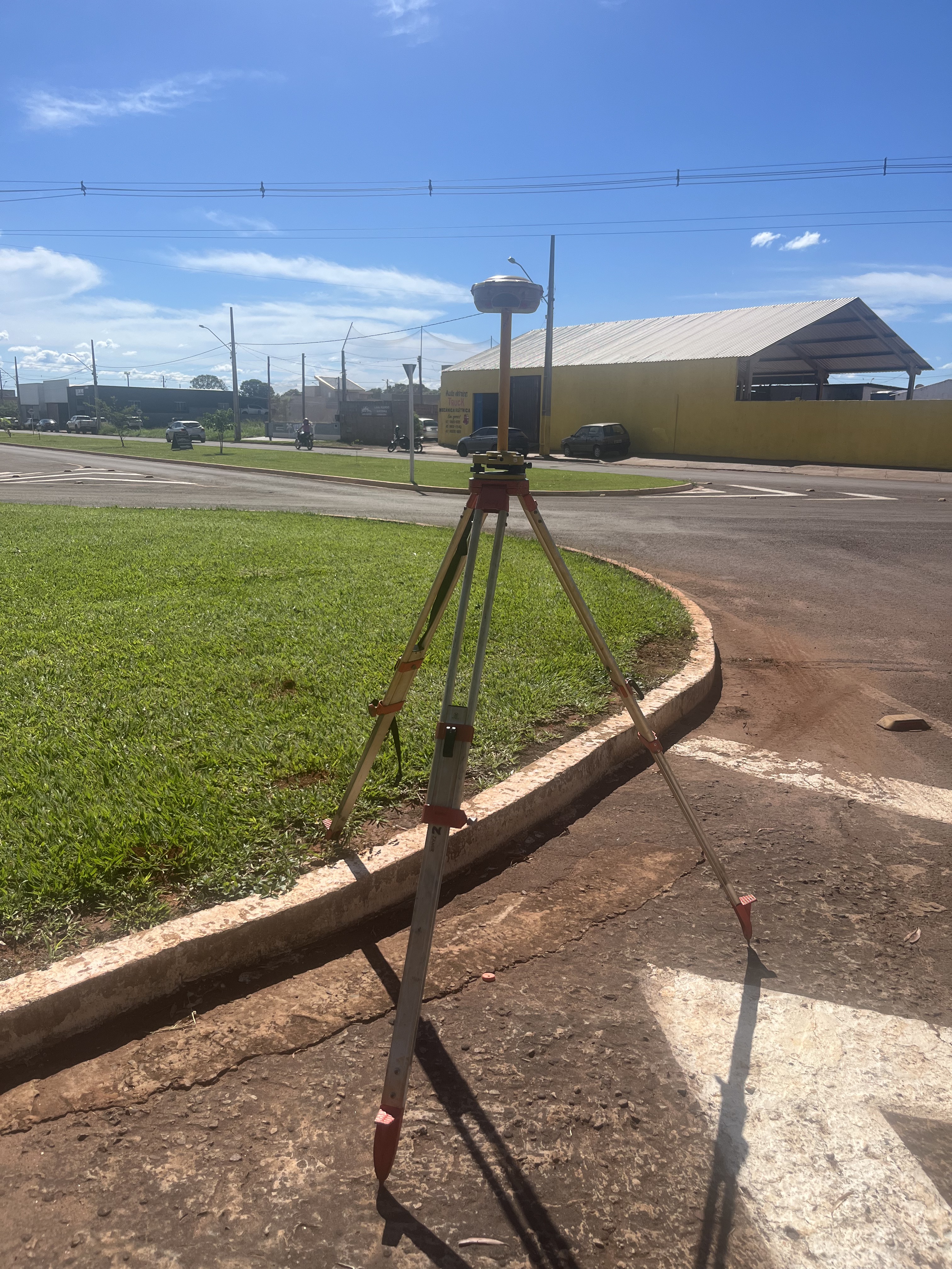 Estação de referência GNSS RTK em tripé durante levantamento topográfico urbano