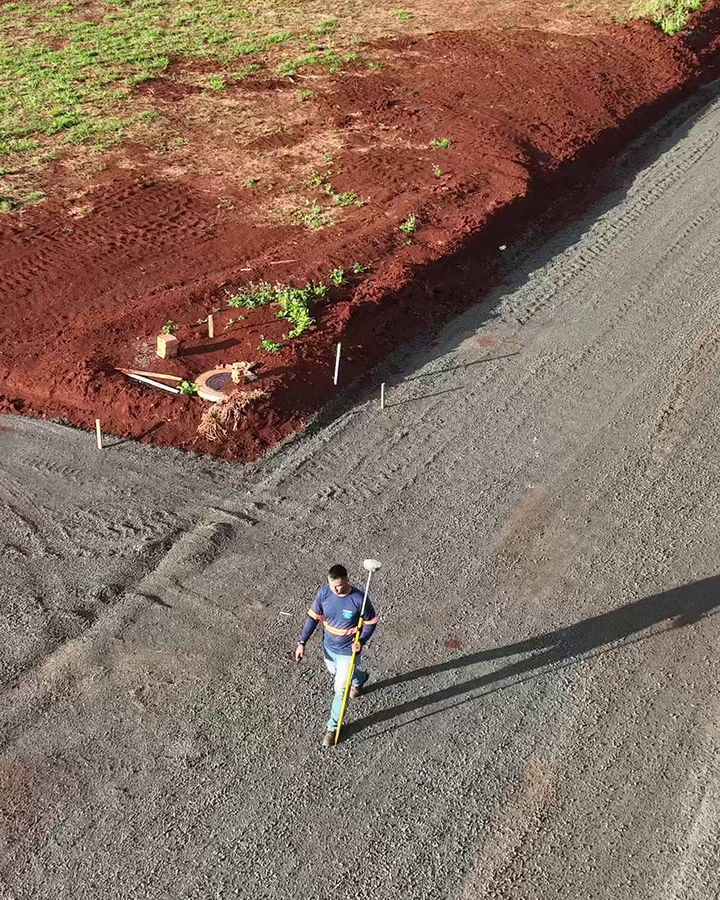 Vista aérea de rua de loteamento com a curva do meio-fio marcada por piquetes