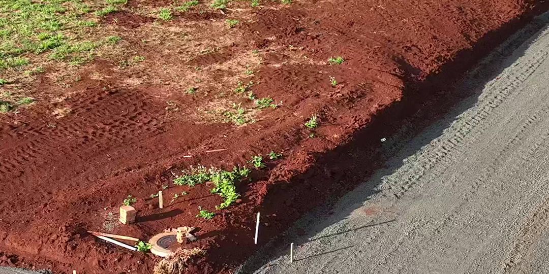 Rua de loteamento com meio-fio marcado por piquetes antes da pavimentação